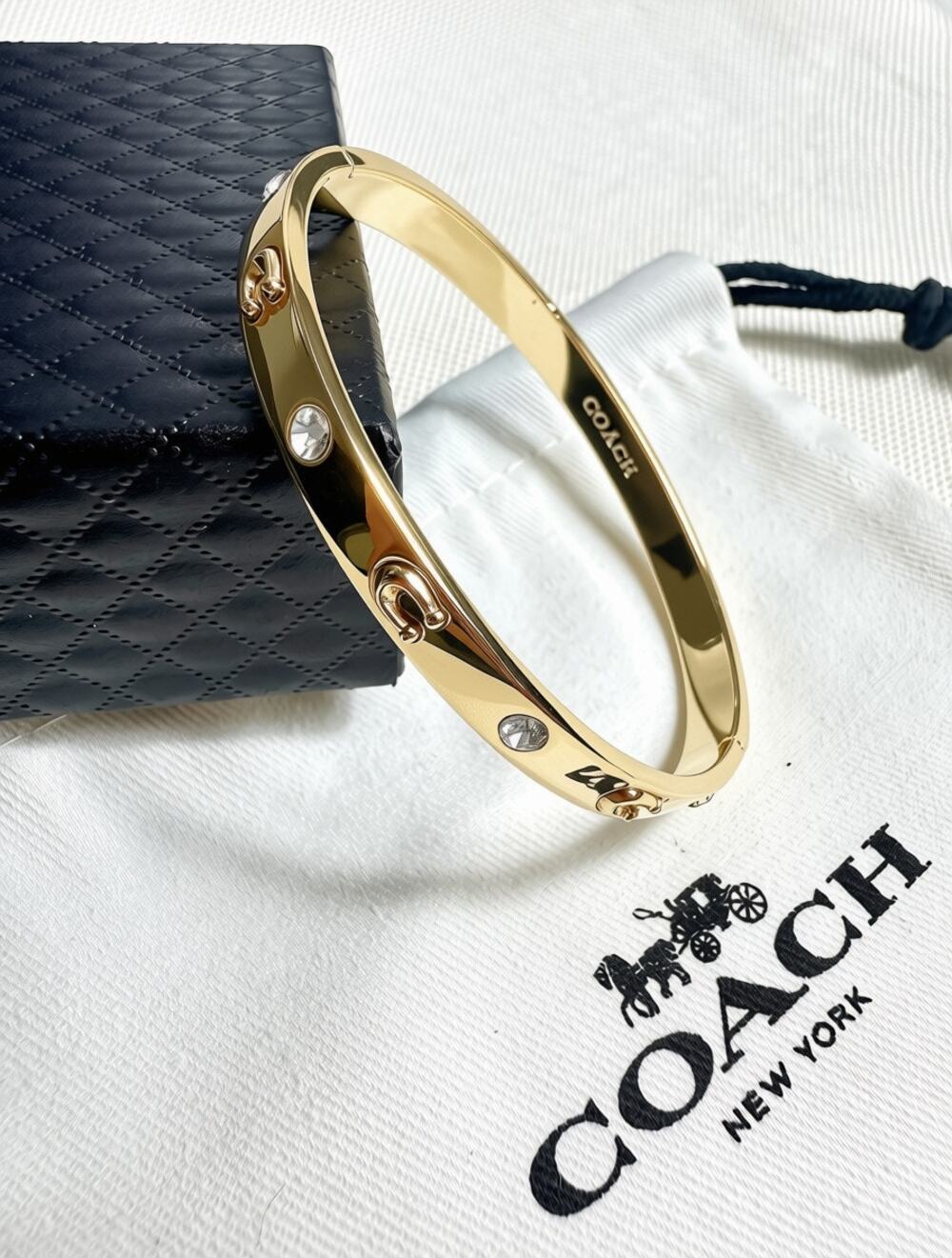 Coach Gold Tone Signature Stone Bangle features sculpted "C"